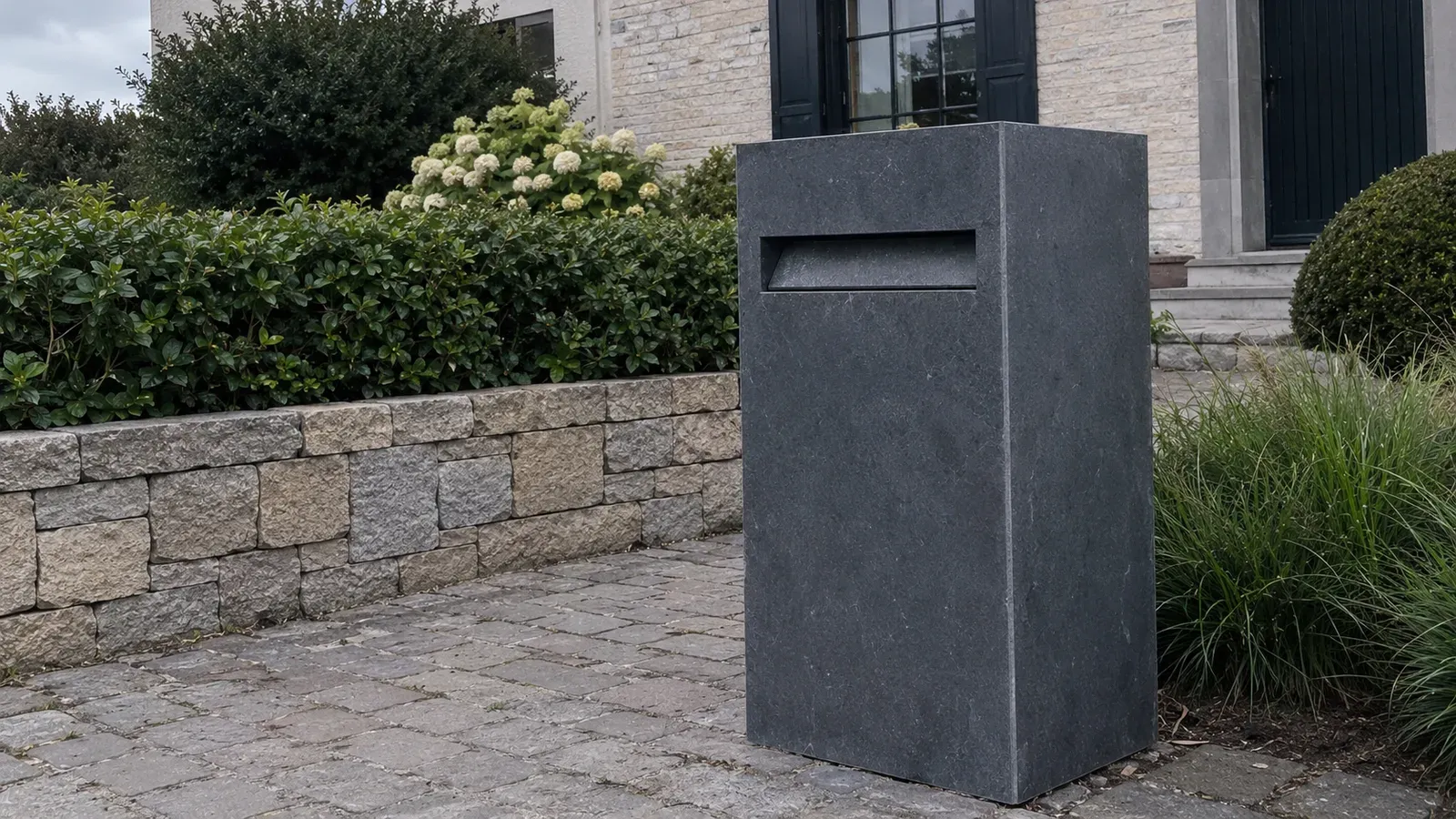 Sfeerbeeld: vrijstaande brievenbus in arduin aan een oprit