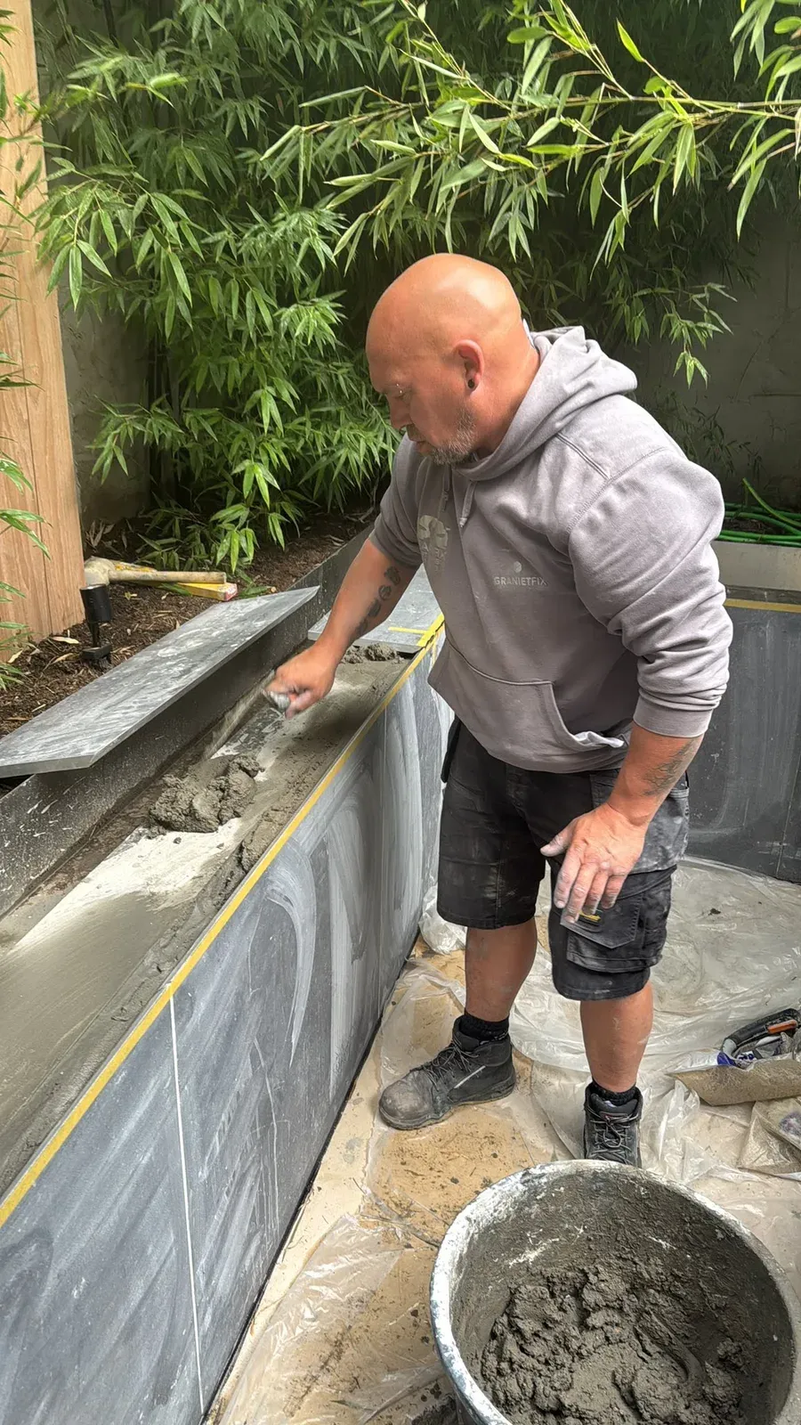 GranietFix-vakman plaatst granieten boordstenen rond een zwemvijver